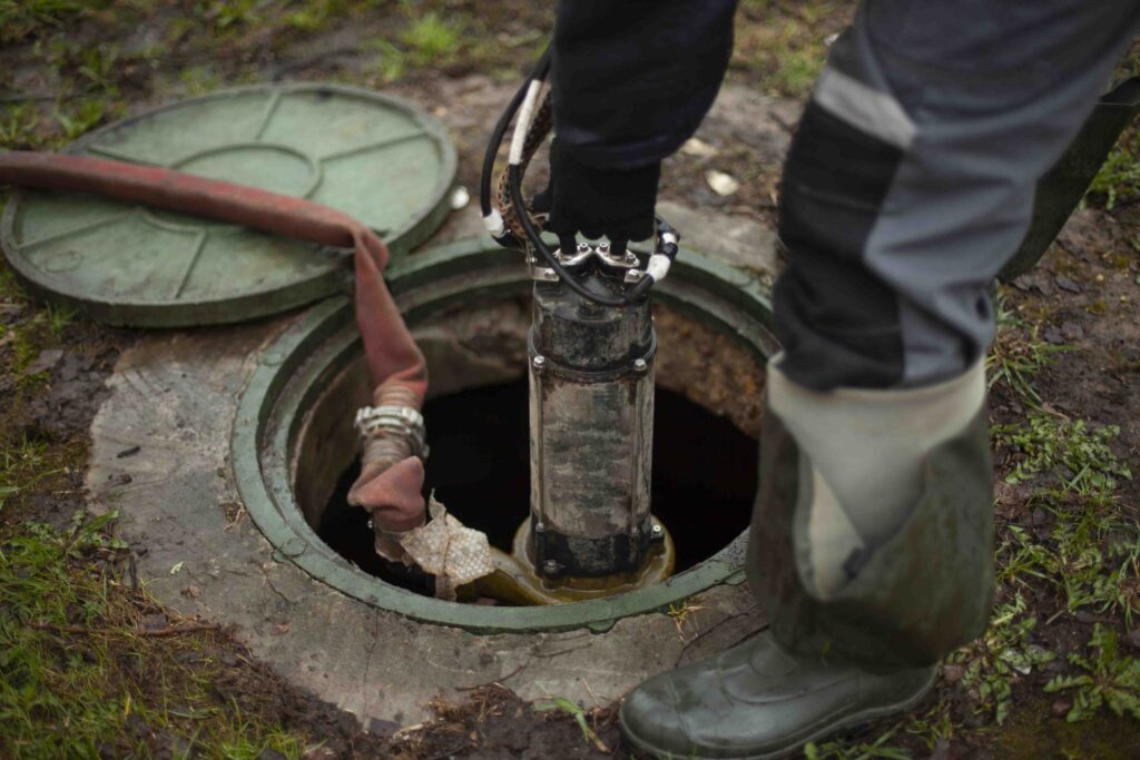 A professional using a hose to clean a septic pump